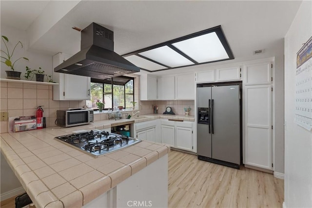 7558 Lobos Ave, Hesperia, CA 92345 - kitchen featuring stainless steel appliances, range hood, tile countertops, light wood-style floors, and a peninsula