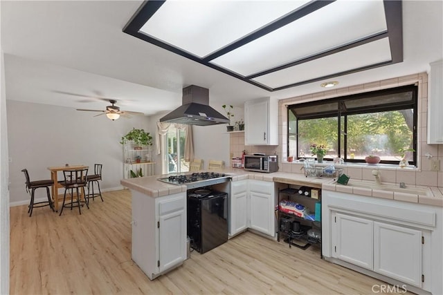7558 Lobos Ave, Hesperia, CA 92345 - kitchen featuring exhaust hood, a peninsula, tile counters, and light wood-style floors