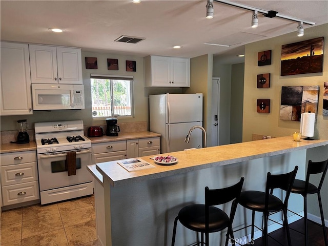 1351 E Gem Cir, Palm Springs, CA 92262 - kitchen with white appliances, track lighting, a kitchen bar, white cabinets, and light countertops
