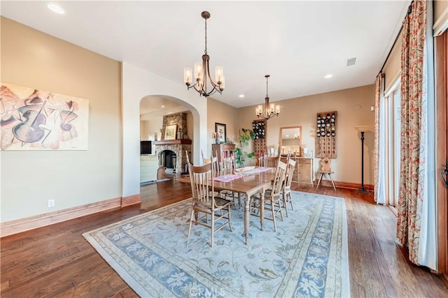 26525 Carancho Rd, Temecula, CA 92590 - dining room featuring a chandelier, a fireplace, dark wood-type flooring, baseboards, and arched walkways