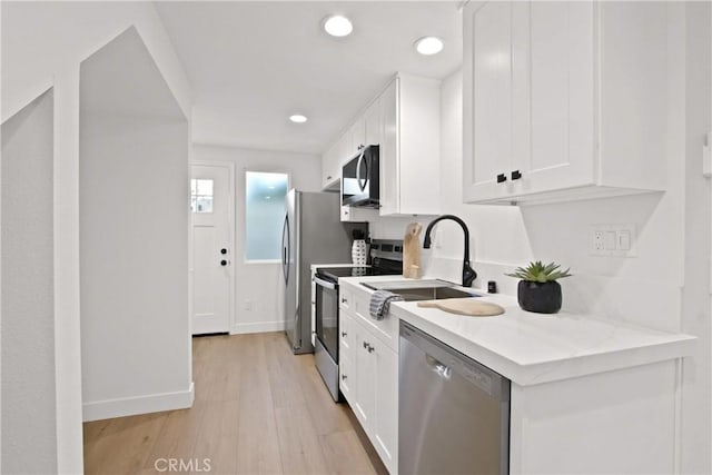 17805 Winterberry St, Fountain Valley, CA 92708 - kitchen with appliances with stainless steel finishes, a sink, white cabinetry, light wood-type flooring, and recessed lighting
