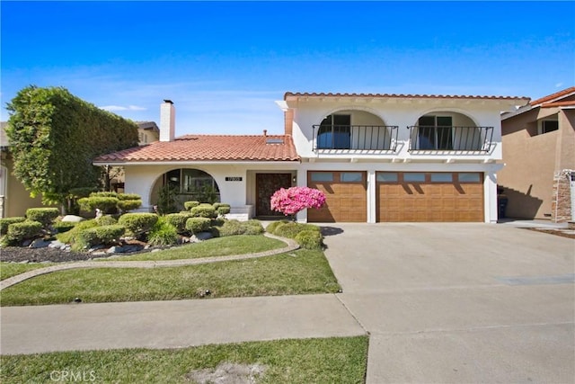 17805 Winterberry St, Fountain Valley, CA 92708 - mediterranean / spanish-style house featuring a balcony, a garage, stucco siding, driveway, and a chimney