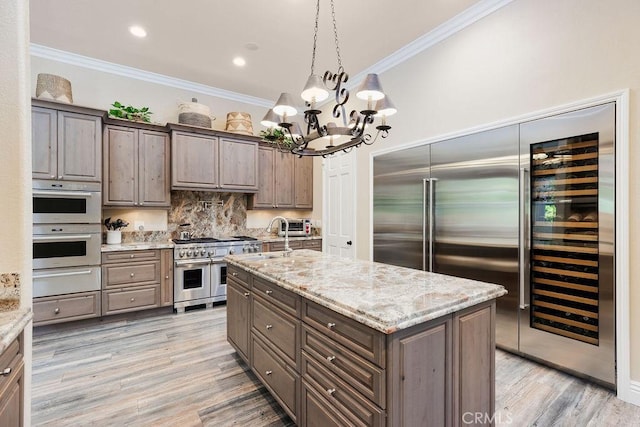 30801 Via Conquista, San Juan Capistrano, CA 92675 - kitchen with premium appliances, crown molding, a chandelier, light wood-style flooring, and light stone counters