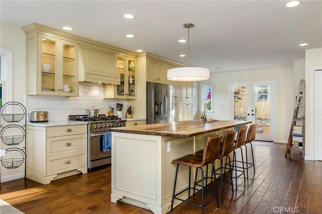 209 Ximeno Ave, Long Beach, CA 90803 - kitchen with appliances with stainless steel finishes, cream cabinetry, custom range hood, dark wood-style floors, and recessed lighting