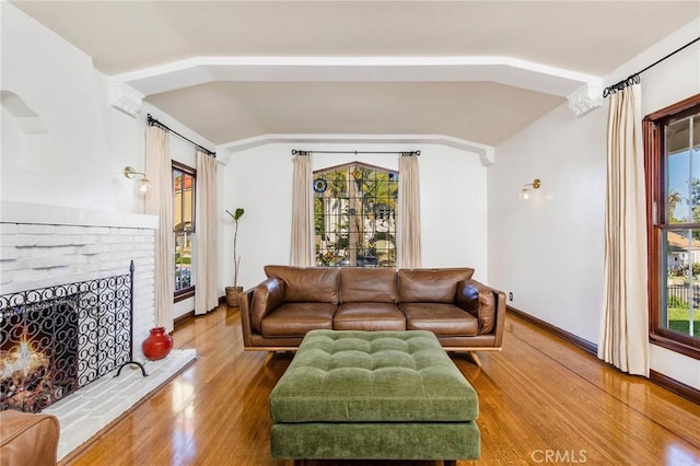 209 Ximeno Ave, Long Beach, CA 90803 - living area featuring vaulted ceiling, wood finished floors, plenty of natural light, a brick fireplace, and baseboards