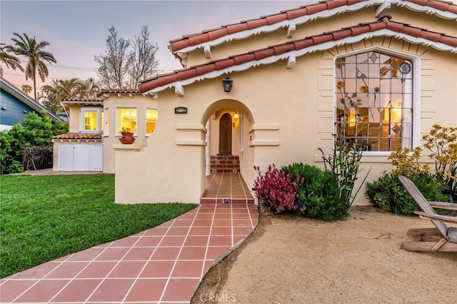 209 Ximeno Ave, Long Beach, CA 90803 - exterior entry at dusk with stucco siding, a tiled roof, and a yard