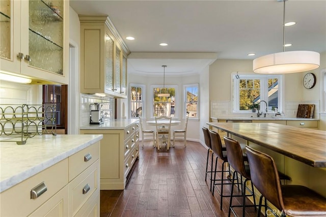 209 Ximeno Ave, Long Beach, CA 90803 - kitchen with cream cabinetry, a breakfast bar, dark wood-type flooring, a sink, and glass insert cabinets