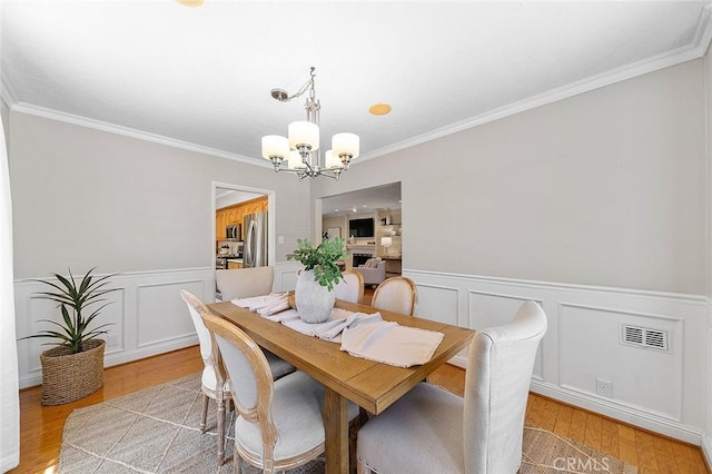 435 Orlena Ave, Long Beach, CA 90814 - dining area featuring a chandelier, ornamental molding, a wainscoted wall, light wood-style flooring, and a decorative wall