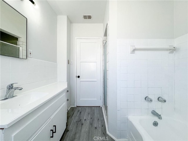 1710 W Arbutus St, Compton, CA 90220 - full bath featuring wood finished floors, vanity, tile walls, and shower / tub combination