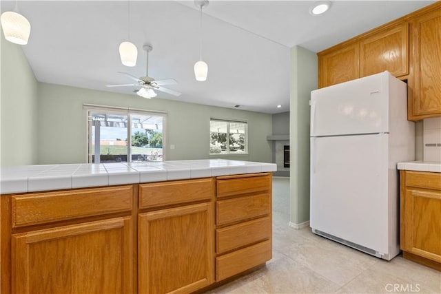 917 Saint Ann, Paso Robles, CA 93446 - kitchen with freestanding refrigerator, a ceiling fan, a fireplace, recessed lighting, and brown cabinets
