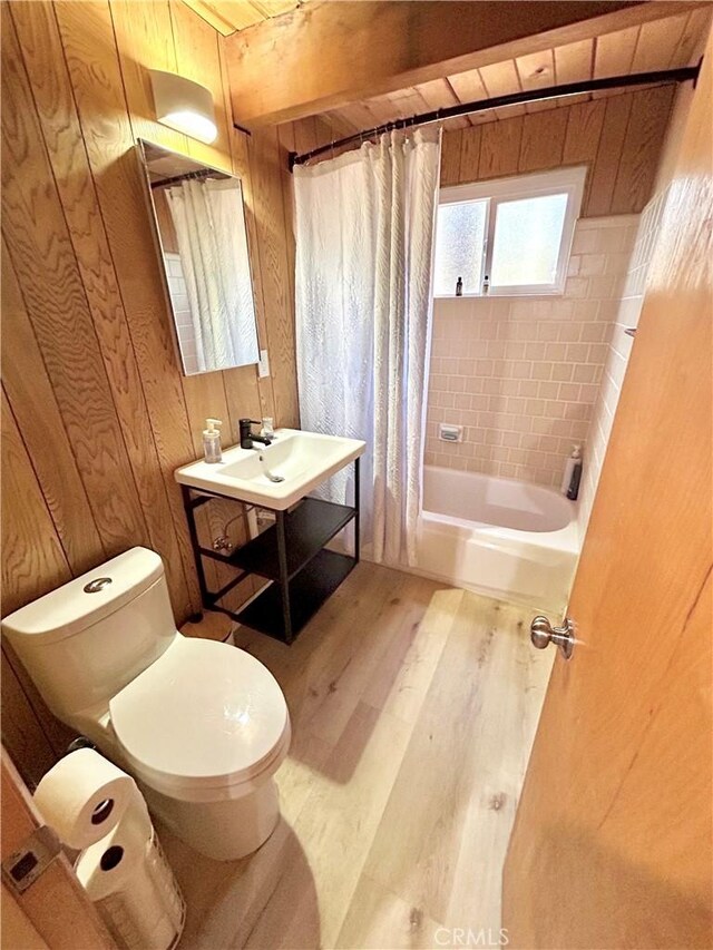 2484 Pine Dr, Running Springs, CA 92382 - full bath featuring wood finished floors, toilet, shower / bath combo with shower curtain, wooden walls, and a sink