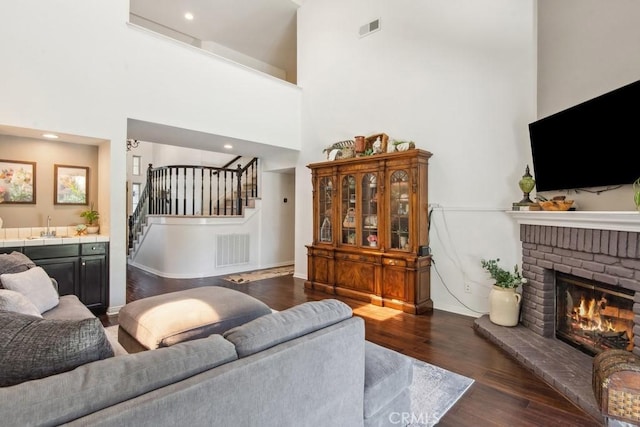 43650 Buckeye Rd, Temecula, CA 92592 - living room with stairs, dark wood-style flooring, a fireplace, and a high ceiling