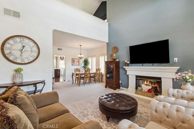 43650 Buckeye Rd, Temecula, CA 92592 - living area featuring a chandelier, carpet flooring, a towering ceiling, and a glass covered fireplace