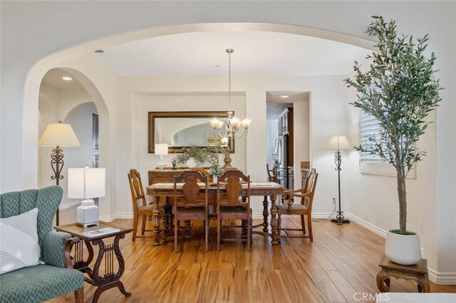 24923 Hearth Ct, Valencia, CA 91354 - dining area with light wood-style flooring, arched walkways, and baseboards
