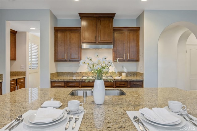 24923 Hearth Ct, Valencia, CA 91354 - kitchen with arched walkways, ventilation hood, light stone counters, recessed lighting, and a sink