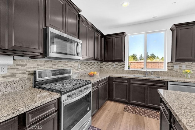 30536 Astoria Ln, Murrieta, CA 92563 - kitchen with appliances with stainless steel finishes, a sink, light wood-style floors, tasteful backsplash, and dark brown cabinets