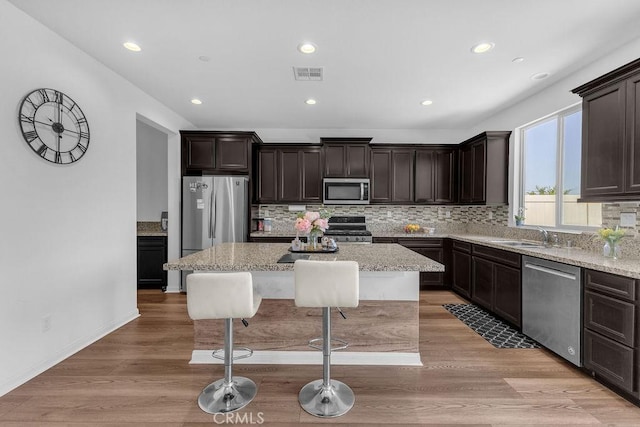 30536 Astoria Ln, Murrieta, CA 92563 - kitchen with appliances with stainless steel finishes, dark brown cabinetry, backsplash, a kitchen island, and recessed lighting