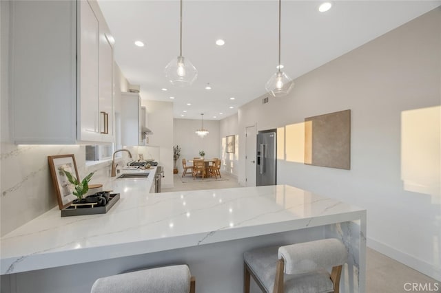 23835 Bella Vista Dr, Newhall, CA 91321 - kitchen featuring stainless steel fridge, light stone counters, recessed lighting, white cabinets, and a kitchen breakfast bar
