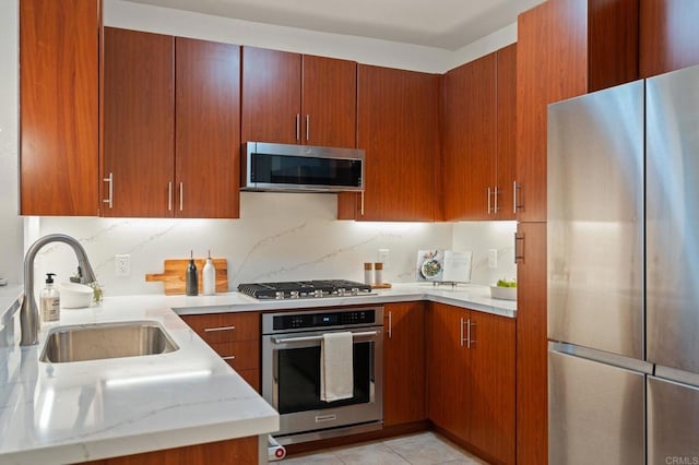 1225 Island Ave Unit 503, San Diego, CA 92101 - kitchen featuring appliances with stainless steel finishes, a sink, decorative backsplash, brown cabinetry, and light stone countertops