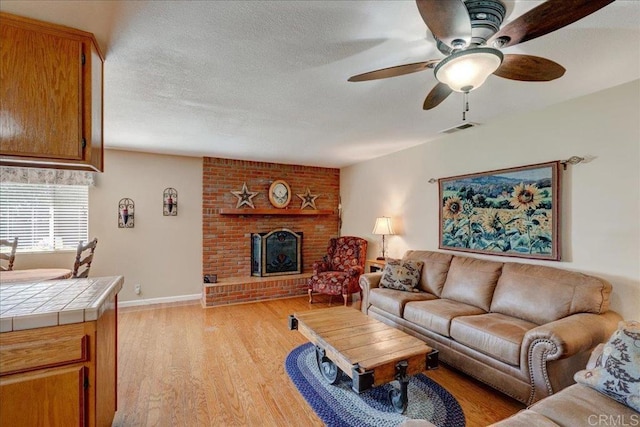 221 E Old Julian Hwy, Ramona, CA 92065 - living room with a ceiling fan, light wood-style floors, a brick fireplace, and baseboards