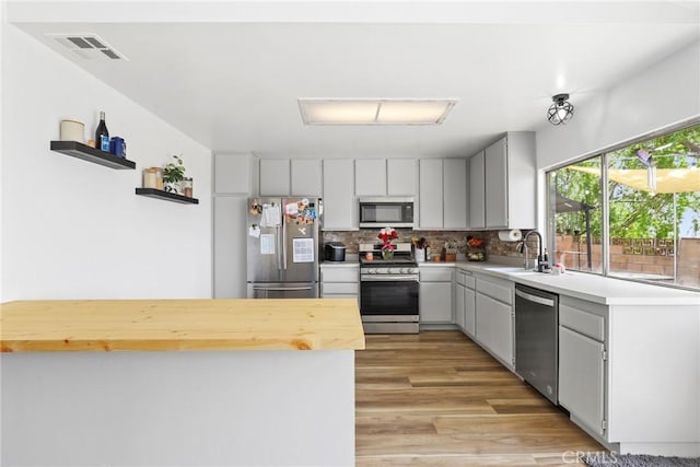 12518 Bernadette St, Pacoima, CA 91331 - kitchen with stainless steel appliances, a sink, light wood finished floors, tasteful backsplash, and wooden counters