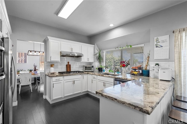 22565 Pecan Pl, Saugus, CA 91390 - kitchen with a sink, under cabinet range hood, a peninsula, white cabinetry, and tasteful backsplash