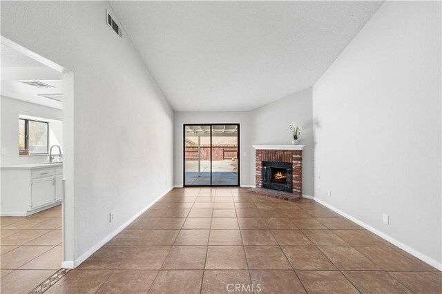 38115 41st St E, Palmdale, CA 93552 - unfurnished living room featuring light tile patterned floors, a brick fireplace, baseboards, and a sink