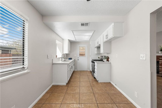 38115 41st St E, Palmdale, CA 93552 - kitchen with stainless steel gas stove, a sink, light countertops, under cabinet range hood, and light tile patterned flooring