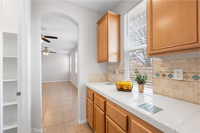 40729 Oakmont Ct, Palmdale, CA 93551 - kitchen featuring light tile patterned floors, a ceiling fan, arched walkways, backsplash, and tile counters