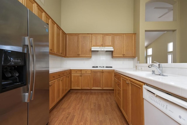 5110 Wisteria Dr, Oceanside, CA 92056 - kitchen featuring stainless steel refrigerator with ice dispenser, white dishwasher, wood finished floors, a sink, and under cabinet range hood
