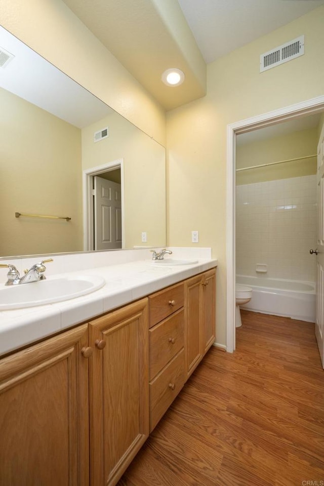 5110 Wisteria Dr, Oceanside, CA 92056 - bathroom featuring double vanity, toilet, wood finished floors, and shower / bathtub combination