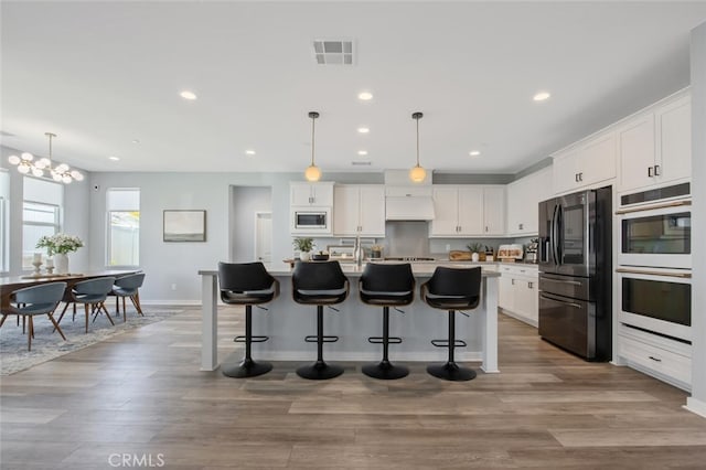18171 Hedgerow Way, Saugus, CA 91350 - kitchen featuring white double oven, stainless steel fridge, built in microwave, a breakfast bar area, and white cabinetry
