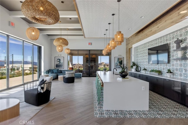 18171 Hedgerow Way, Saugus, CA 91350 - kitchen with wood finished floors, a kitchen island with sink, decorative light fixtures, a towering ceiling, and open floor plan