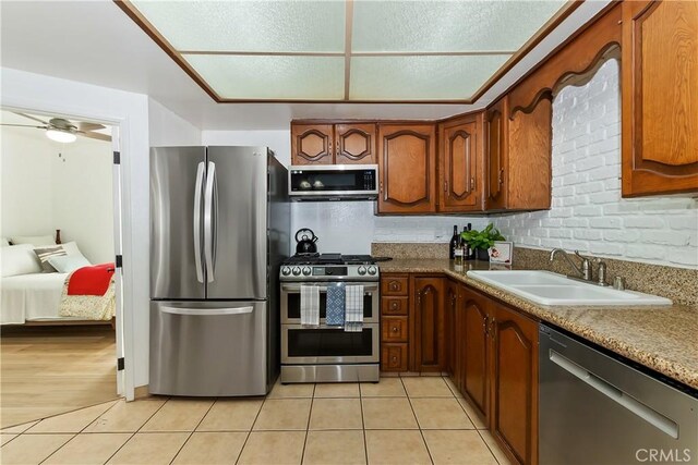 22771 Fir Ln, Crestline, CA 92325 - kitchen with appliances with stainless steel finishes, a sink, light tile patterned flooring, brown cabinets, and a ceiling fan