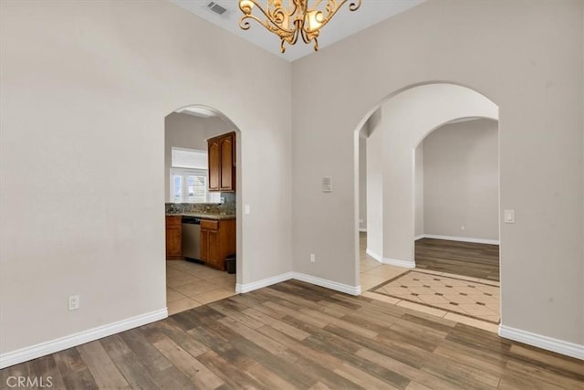 17322 Danbury Ave, Hesperia, CA 92345 - unfurnished room with light wood finished floors, a chandelier, and arched walkways