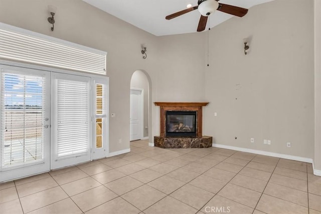 17322 Danbury Ave, Hesperia, CA 92345 - unfurnished living room with a ceiling fan, light tile patterned flooring, arched walkways, a glass covered fireplace, and high vaulted ceiling