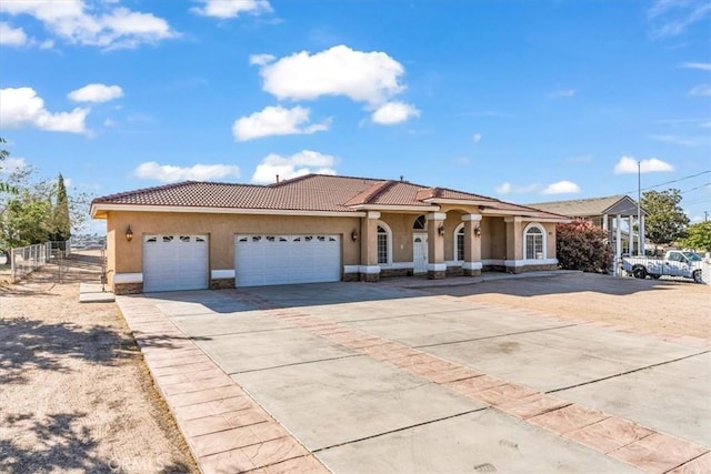 17322 Danbury Ave, Hesperia, CA 92345 - mediterranean / spanish-style house featuring stucco siding, concrete driveway, an attached garage, stone siding, and a tiled roof