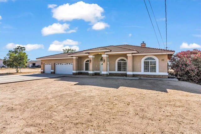 17322 Danbury Ave, Hesperia, CA 92345 - mediterranean / spanish-style house featuring a tile roof, a chimney, stucco siding, and a garage