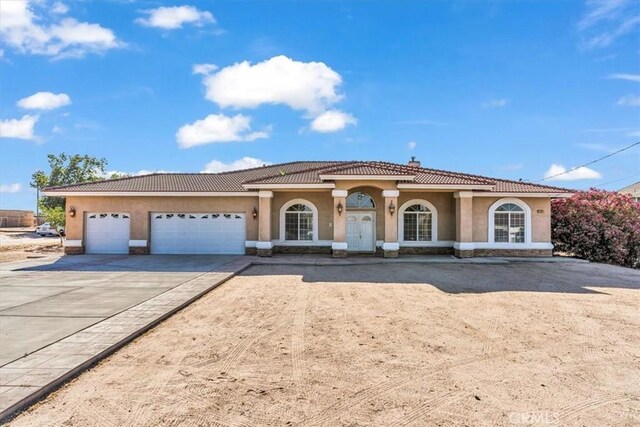 17322 Danbury Ave, Hesperia, CA 92345 - mediterranean / spanish-style house featuring driveway, stucco siding, an attached garage, and a tiled roof