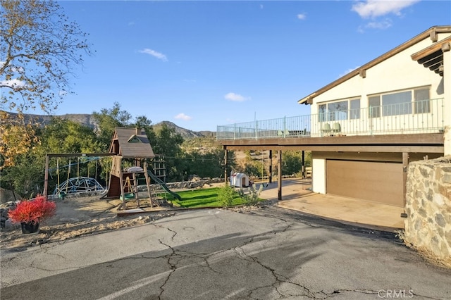 44310 Calle Bernardo, Temecula, CA 92590 - view of front of house with a playground, a garage, a mountain view, asphalt driveway, and a balcony