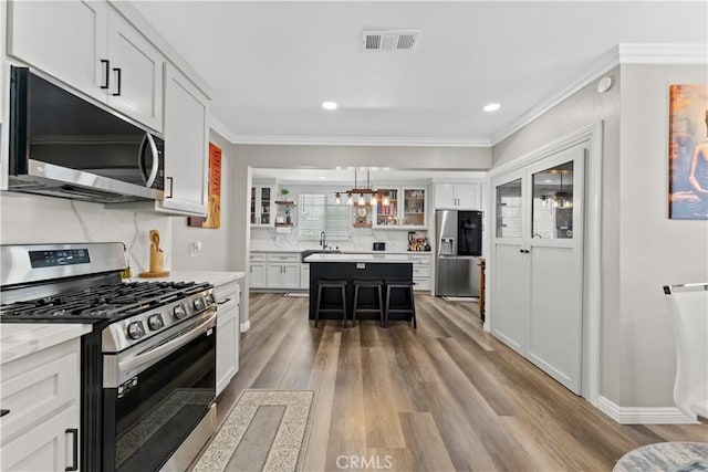 1422 S Exmoor Ave, Compton, CA 90220 - kitchen with appliances with stainless steel finishes, a sink, light wood finished floors, light countertops, and a breakfast bar