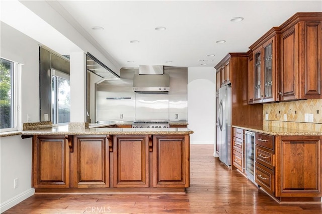 32911 Danaoak, Dana Point, CA 92629 - kitchen with freestanding refrigerator, wine cooler, wall chimney exhaust hood, brown cabinets, and light stone counters