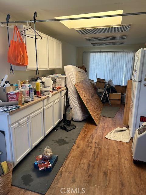 38833 Sage Tree St, Palmdale, CA 93551 - kitchen with wood finished floors, white cabinets, freestanding refrigerator, and light countertops