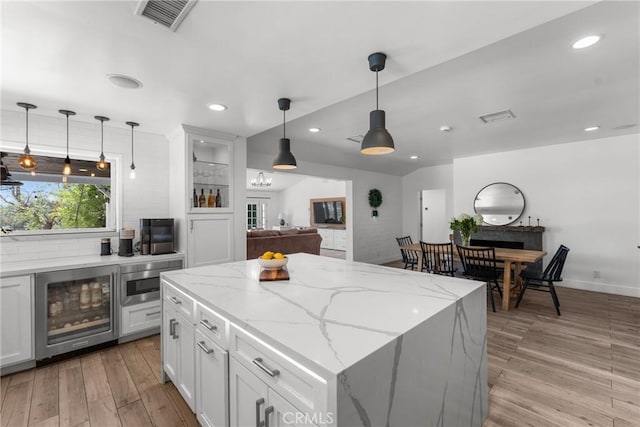 4674 Norton Pl, Riverside, CA 92506 - kitchen featuring wine cooler, light wood-style floors, white cabinetry, recessed lighting, and a kitchen island