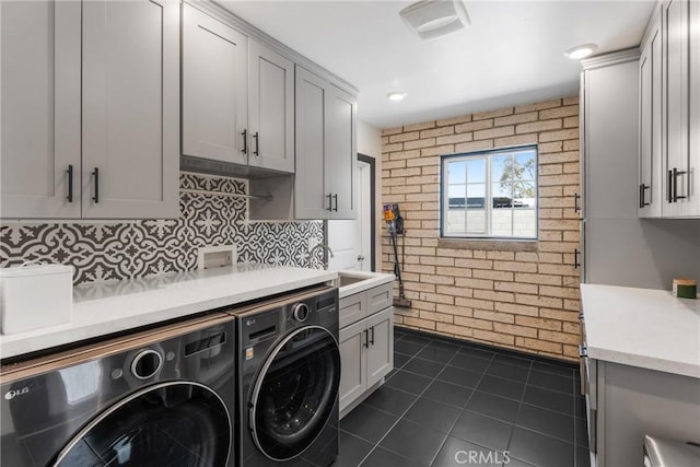 4674 Norton Pl, Riverside, CA 92506 - laundry area with cabinet space, washer and clothes dryer, brick wall, and dark tile patterned flooring