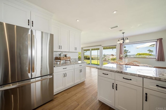 3890 Vista Campana S Unit 35, Oceanside, CA 92057 - kitchen with freestanding refrigerator, a chandelier, light wood-style flooring, white cabinets, and hanging light fixtures