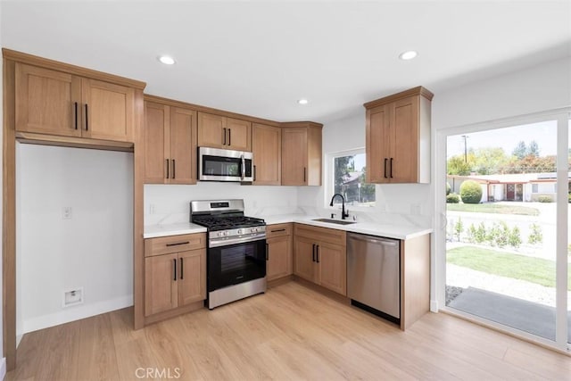 22306 Marlin Pl, Canoga Park, CA 91303 - kitchen featuring appliances with stainless steel finishes, a sink, light countertops, light wood-style flooring, and brown cabinetry