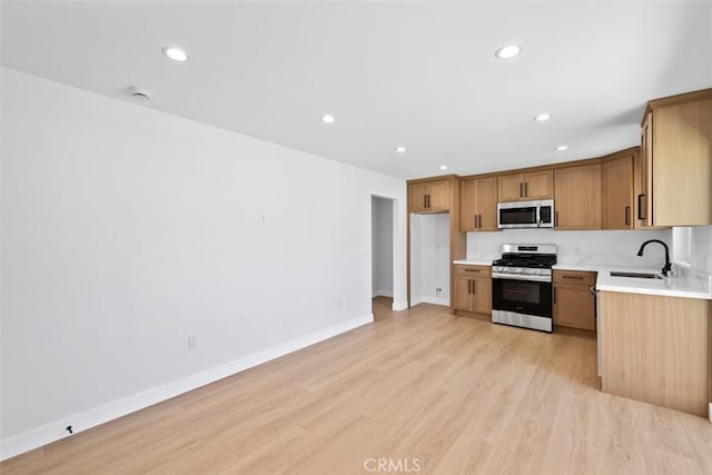 22306 Marlin Pl, Canoga Park, CA 91303 - kitchen featuring stainless steel appliances, a sink, light countertops, recessed lighting, and light wood-style floors