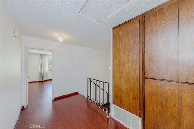 5021 Peck Rd Unit 9, El Monte, CA 91732 - hall with an upstairs landing, dark wood-style flooring, attic access, a textured ceiling, and baseboards