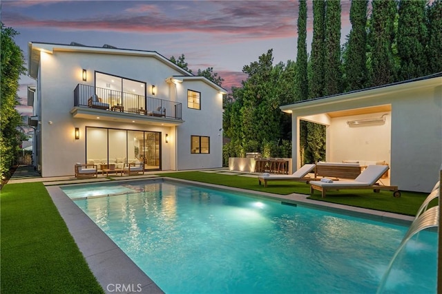 4625 Vesper Ave, Sherman Oaks, CA 91403 - back of house at dusk with a balcony, outdoor lounge area, a yard, an outdoor pool, and stucco siding
